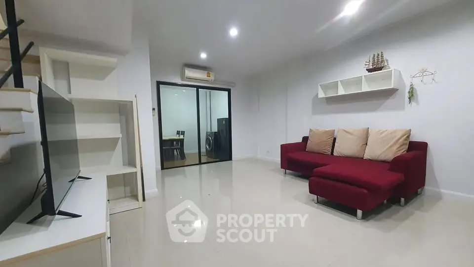 Spacious modern living room with red sofa and open layout, perfect for relaxation and entertainment.