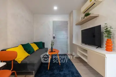 Modern living room with stylish decor, vibrant cushions, and sleek furniture in a cozy apartment.