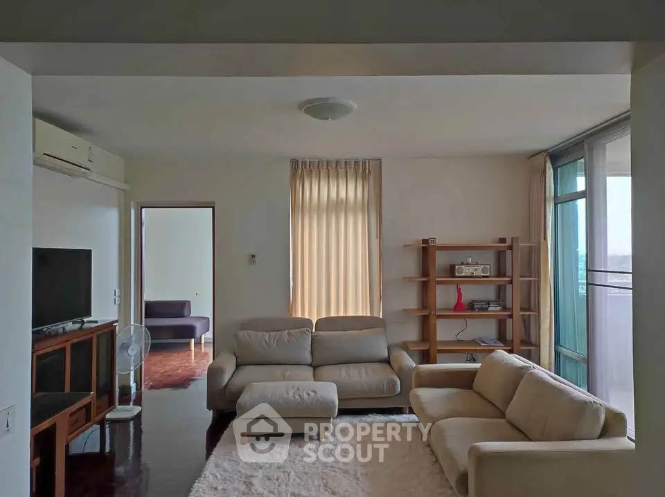 Spacious living room with modern furniture and natural light, featuring a cozy seating area and stylish decor.