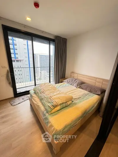 Modern bedroom with city view and large windows in high-rise apartment.