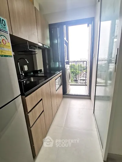 Modern kitchen with sleek cabinetry and balcony access in urban apartment