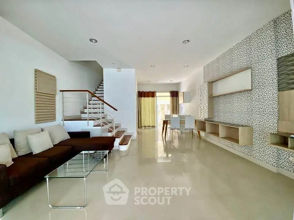 Spacious modern living room with elegant staircase and dining area, perfect for family gatherings.