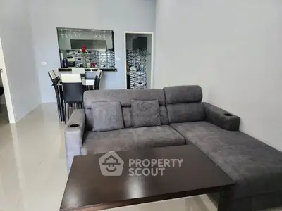 Modern living room with stylish gray sofa and sleek dining area in open layout.