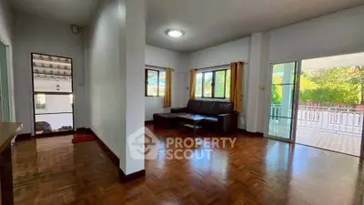 Spacious living room with hardwood floors and large windows offering natural light and garden view.