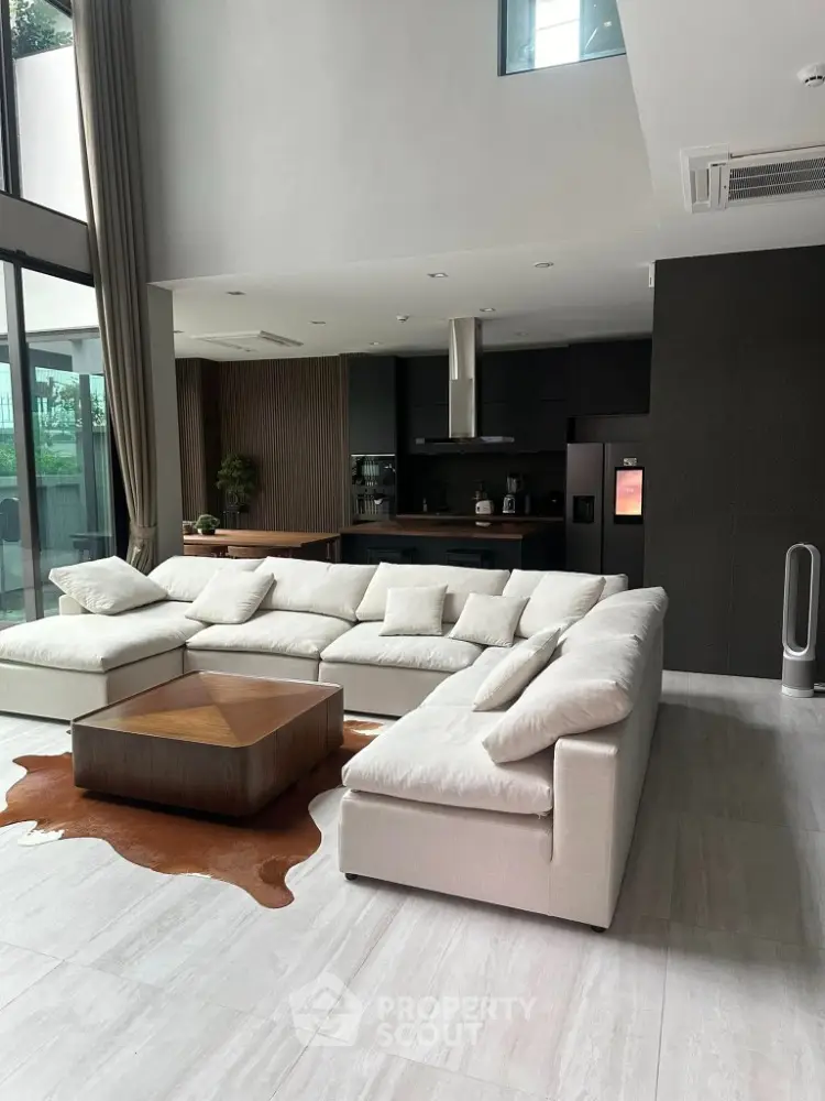 Spacious modern living room with large sofa and open kitchen layout