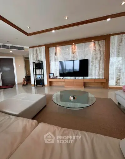 Spacious living room with modern decor and large TV, perfect for entertainment and relaxation.