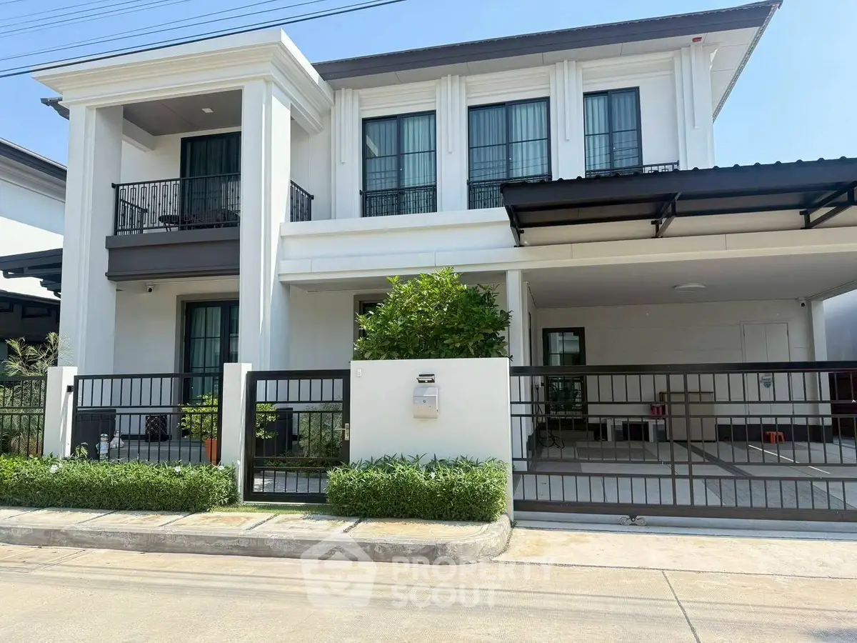 Elegant two-story modern house with balcony and gated driveway in a serene neighborhood.