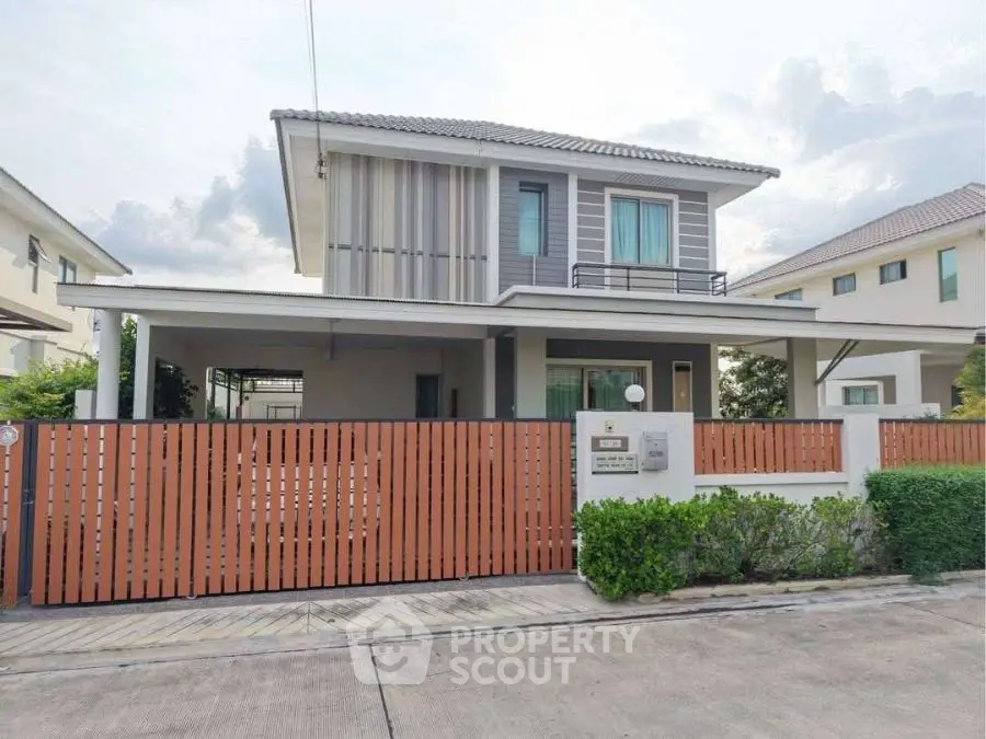 Modern two-story house with stylish facade and gated entrance in suburban neighborhood.
