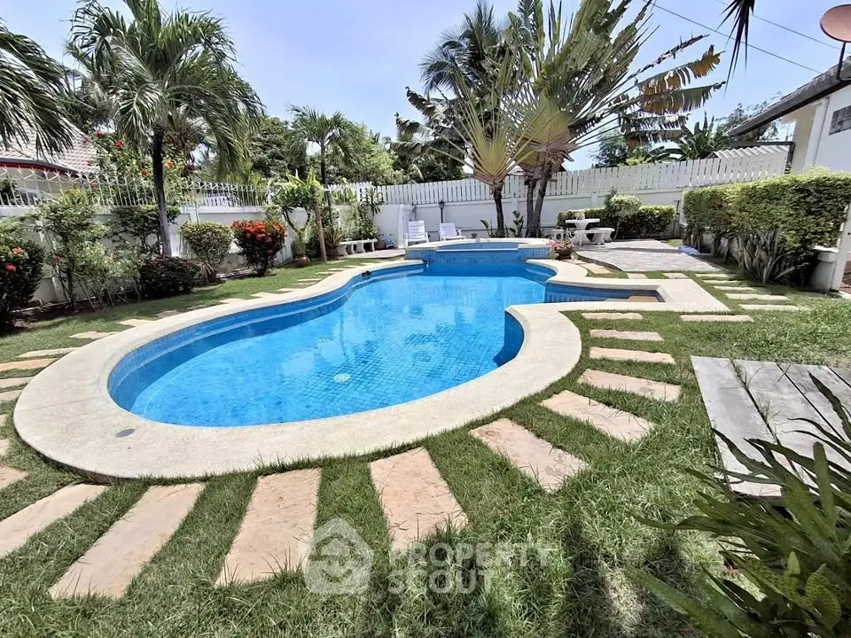 Luxurious backyard pool surrounded by lush greenery and tropical plants, perfect for relaxation.
