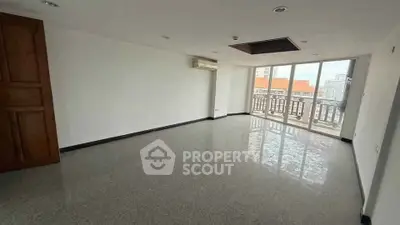 Spacious empty living room with large windows and city view balcony.