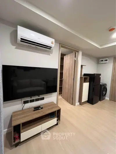 Modern living room with sleek TV setup and air conditioning in stylish apartment.