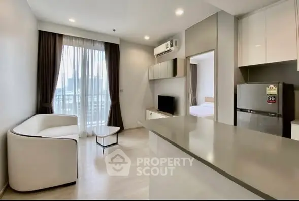 Modern open-plan living room with sleek kitchen and balcony view