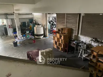 Spacious industrial storage area with boxes and machinery, ideal for manufacturing or warehousing needs.