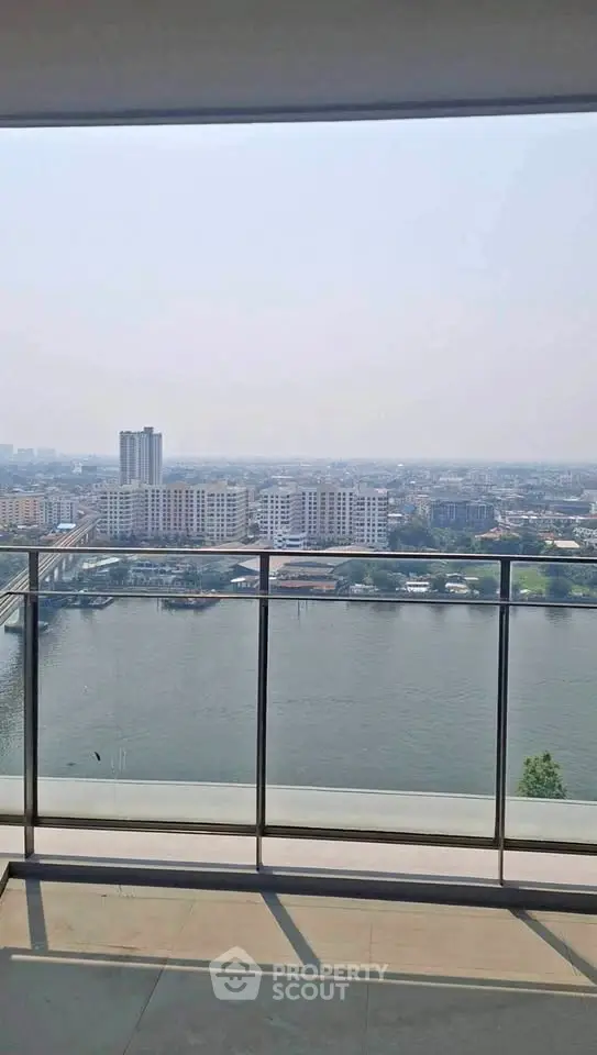 Stunning high-rise balcony view overlooking a serene river and cityscape, perfect for urban living.