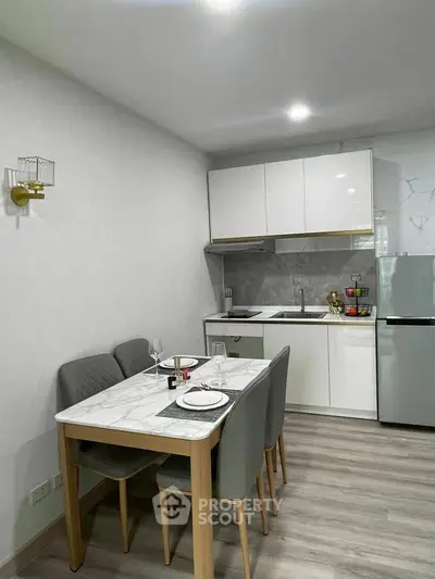 Modern kitchen with sleek white cabinets and dining area in a stylish apartment.
