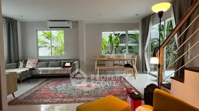 Spacious living room with modern decor and large windows overlooking greenery.