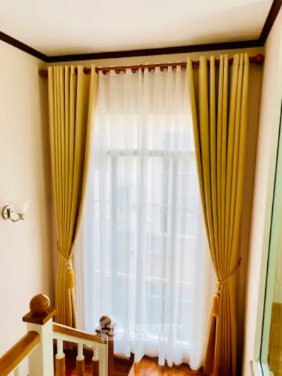 Elegant staircase with floor-to-ceiling window and luxurious curtains