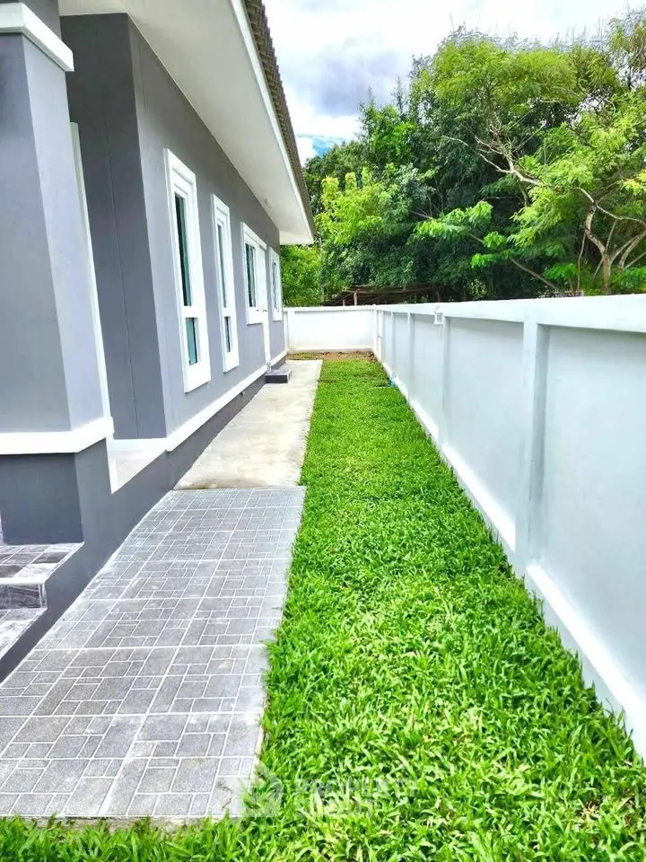 Modern home exterior with lush green lawn and sleek grey facade.