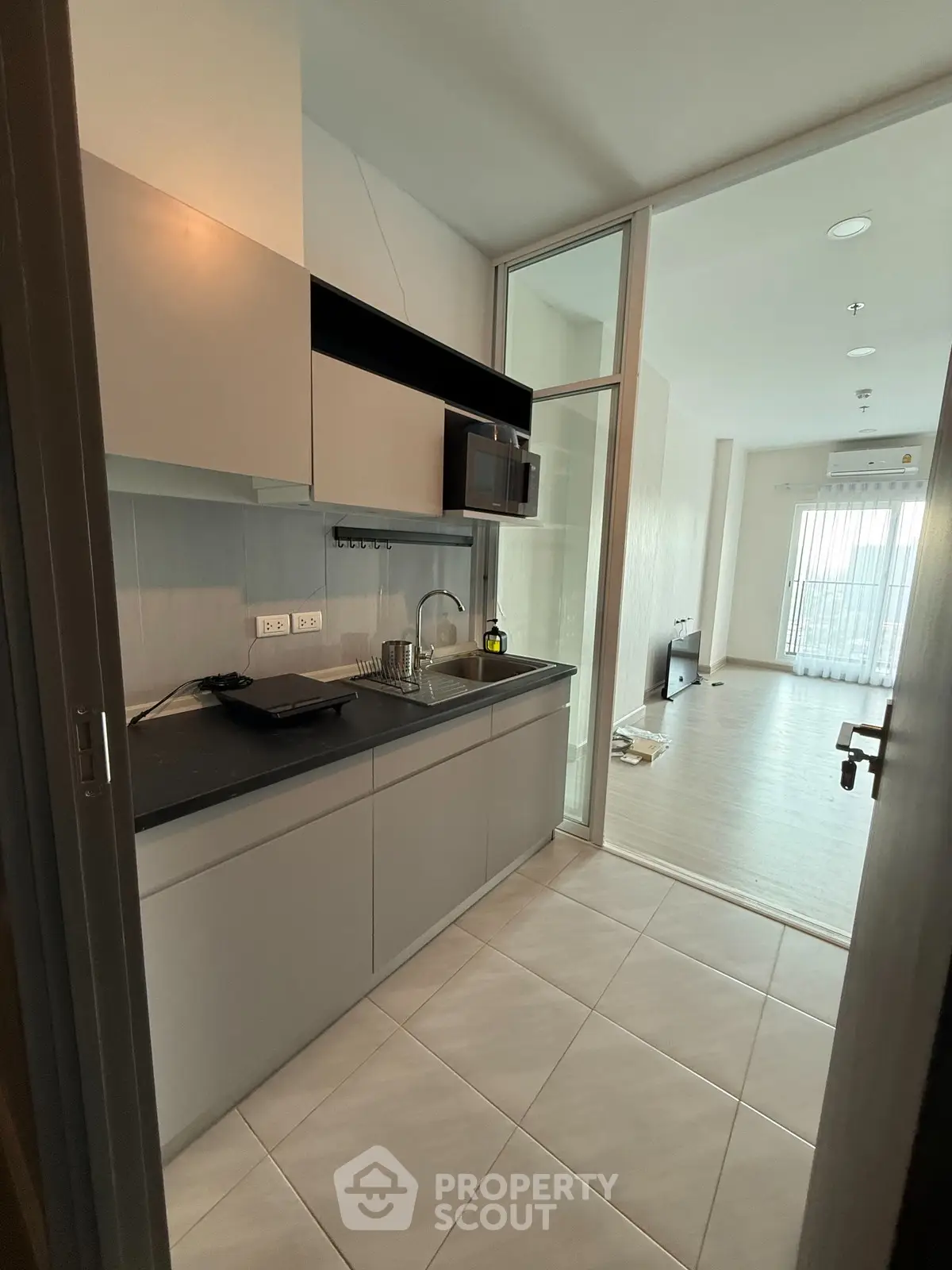 Modern kitchen with sleek cabinetry and open layout leading to bright living area