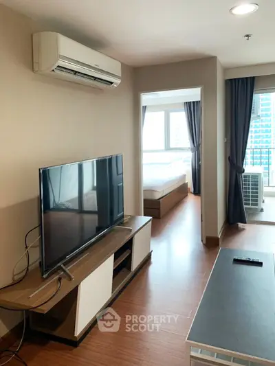 Modern apartment interior with TV and air conditioning, featuring a view into a cozy bedroom.