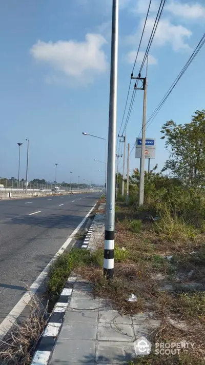 Expansive roadside view with clear skies and utility poles, ideal for commercial development.