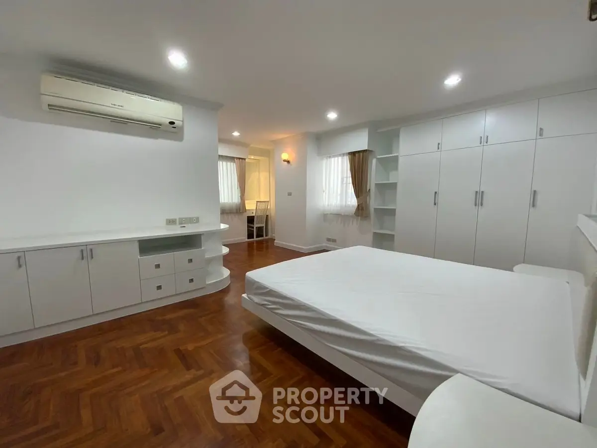 Spacious bedroom with modern white furniture and wooden flooring