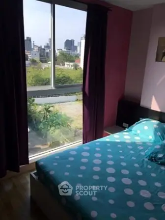 Cozy bedroom with large window offering stunning city view and vibrant decor.