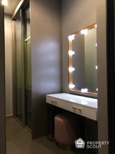 Elegant vanity area with Hollywood-style lighted mirror and modern finishes, perfect for a touch of luxury in a cozy space.