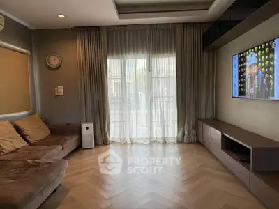 Modern living room with cozy sofa, wall-mounted TV, and elegant curtains.