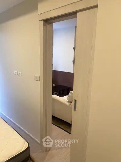 Modern interior with sliding door leading to cozy living area, showcasing minimalist design and neutral tones.