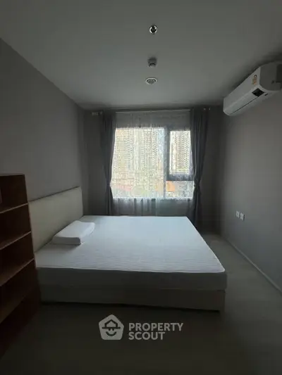 Spacious bedroom with large window and air conditioning in modern apartment.