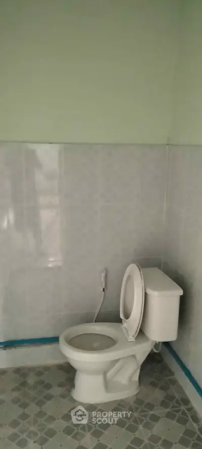 Simple bathroom with tiled walls and floor, featuring a standard toilet.