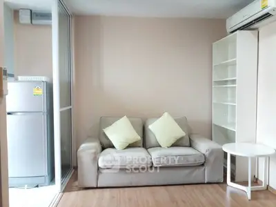 Cozy living room with sofa, air conditioning, and adjacent kitchen area.