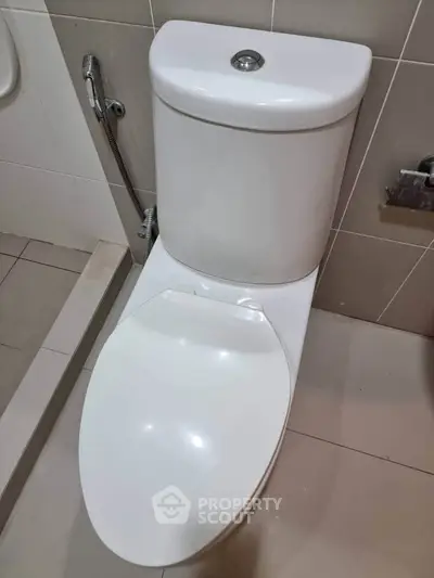 Modern bathroom with sleek white toilet and tiled walls, perfect for contemporary living.
