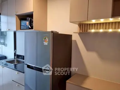 Modern kitchen with sleek fridge and stylish cabinetry in a contemporary apartment.