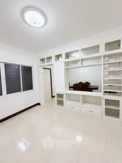 Spacious living room with built-in shelves and dining area in modern apartment