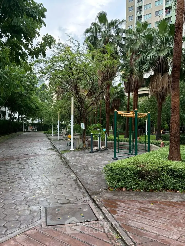 Beautiful garden area with lush greenery and outdoor fitness equipment in a residential complex.
