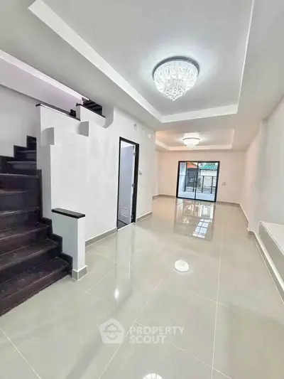 Spacious modern living room with elegant staircase and chandelier lighting