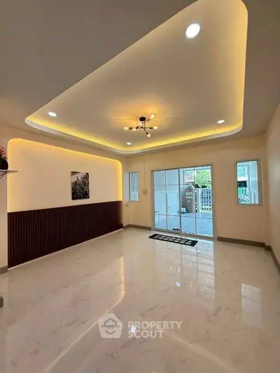 Spacious modern living room with elegant ceiling lights and large windows.