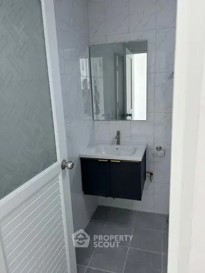 Modern bathroom with sleek vanity and large mirror in a minimalist design.