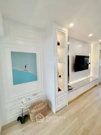 Elegant living room with modern decor and wall-mounted TV, featuring stylish white paneling and light wood flooring.