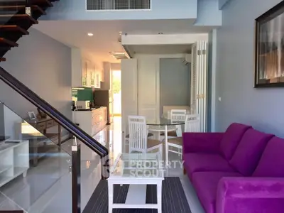 Modern living room with vibrant purple sofa and sleek glass staircase