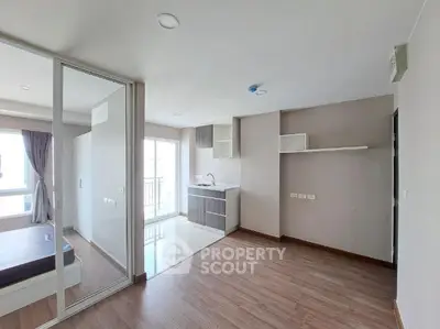 Modern open-plan studio apartment with sleek kitchen and wooden flooring.