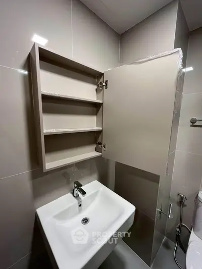Modern bathroom with sleek sink and open cabinet showcasing ample storage space.