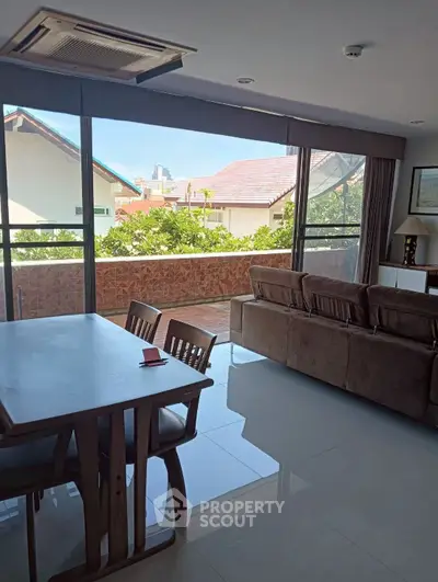Spacious living room with large windows opening to a balcony with scenic views.