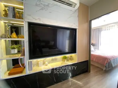 Modern living room with stylish decor and large TV, adjacent to a cozy bedroom with natural light.