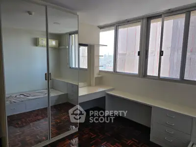 Spacious bedroom with mirrored wardrobe and city view windows