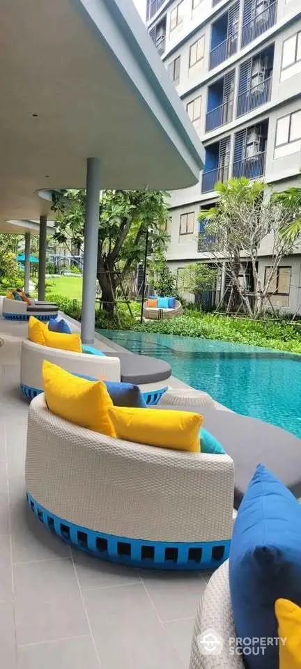 Luxurious poolside seating area with vibrant cushions in modern residential complex