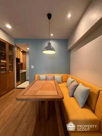 Stylish dining area with cozy yellow seating and modern lighting in a contemporary home.