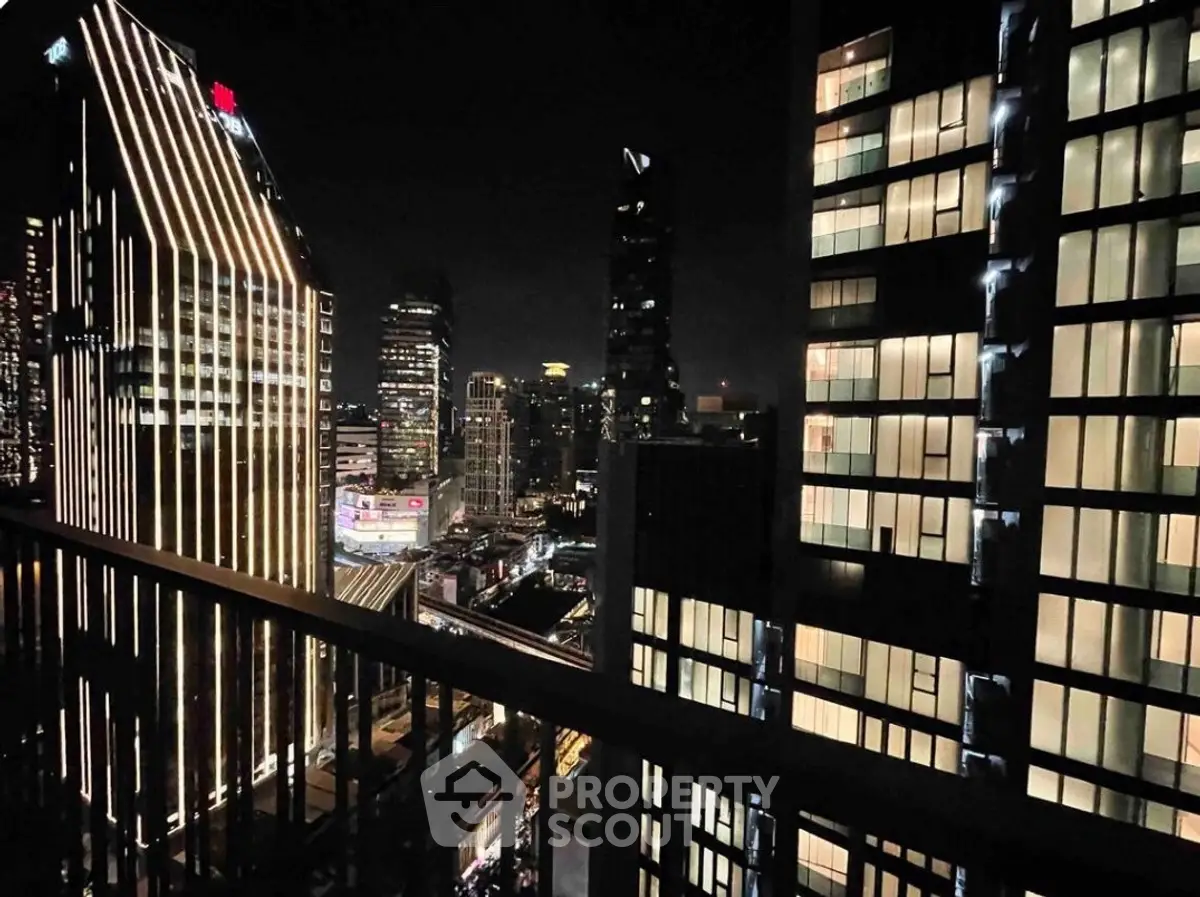 Stunning cityscape night view from high-rise balcony with illuminated skyscrapers.